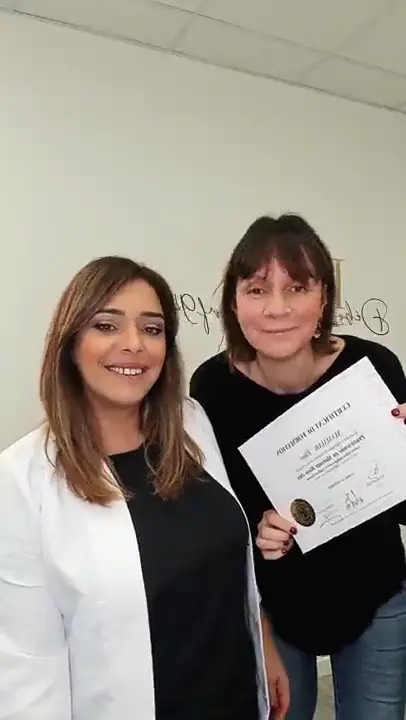 La formatrice en blouse blanche et une stagiaire tenant son attestation, côte à côte.