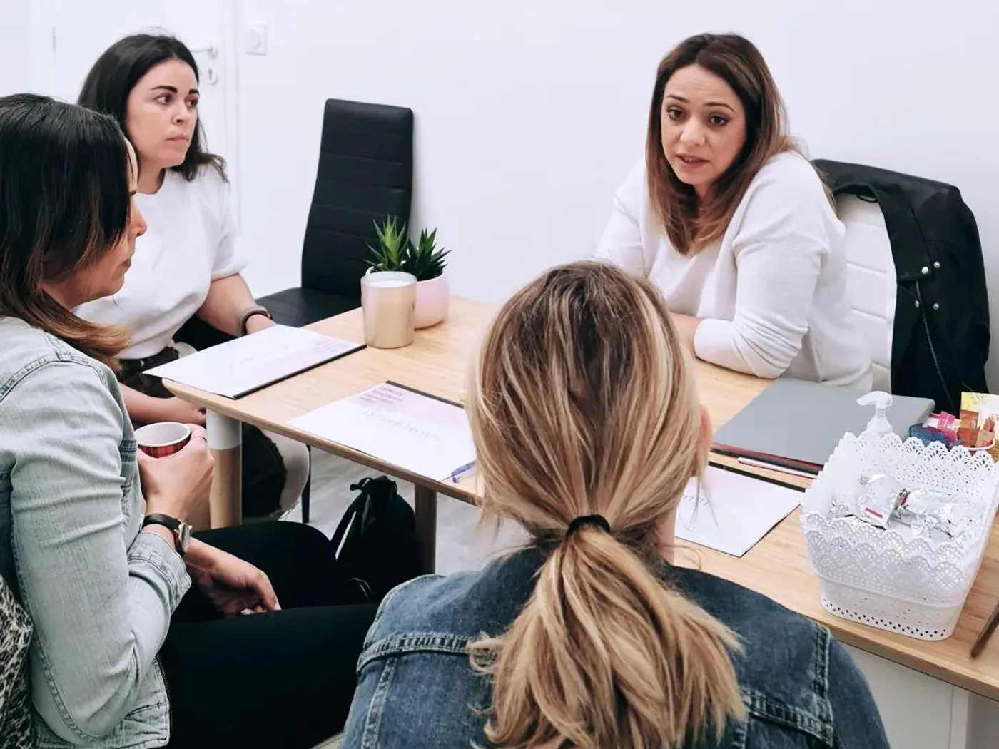 La salle de formation : une table de bois clair, trois postes de travail, un plafonnier de dalles blanches.